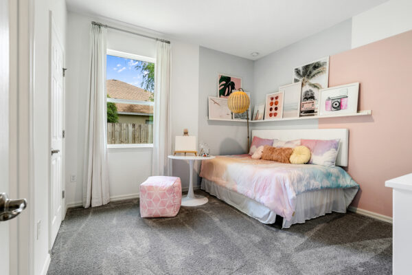 A girl's pink bedroom in the Captiva floorplan from the Cornerstone collection by Holiday Builders.