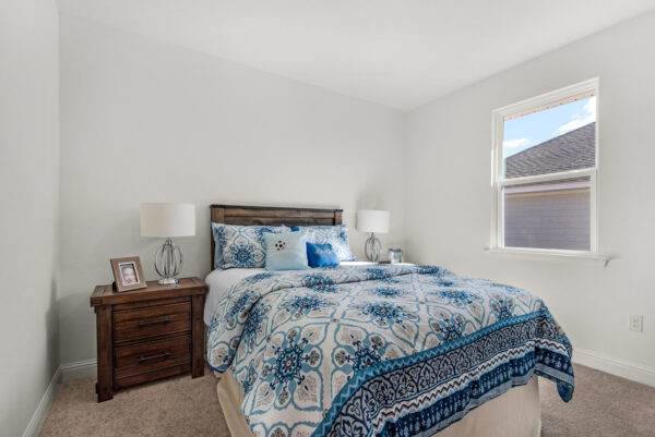 A blue guest bedroom in the Cypress floorplan from the Cornerstone collection by Holiday Builders.