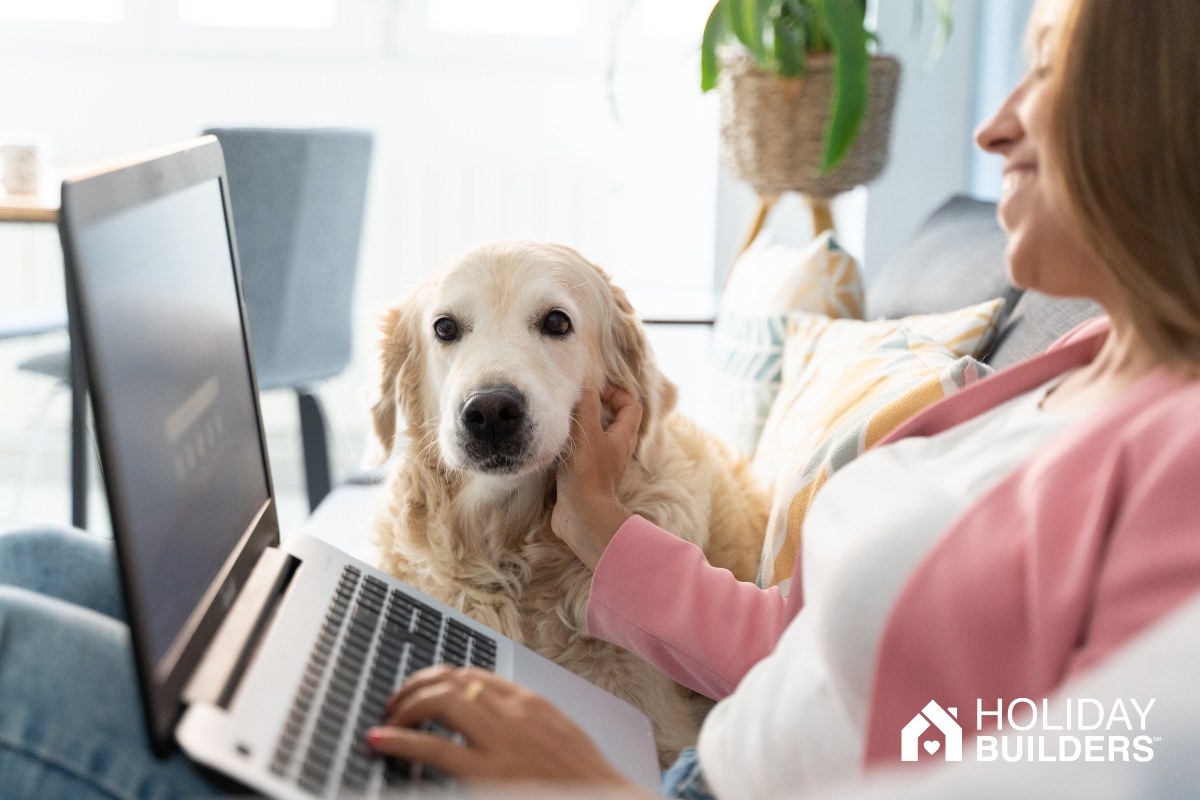Woman on couch with dog, looking at laptop