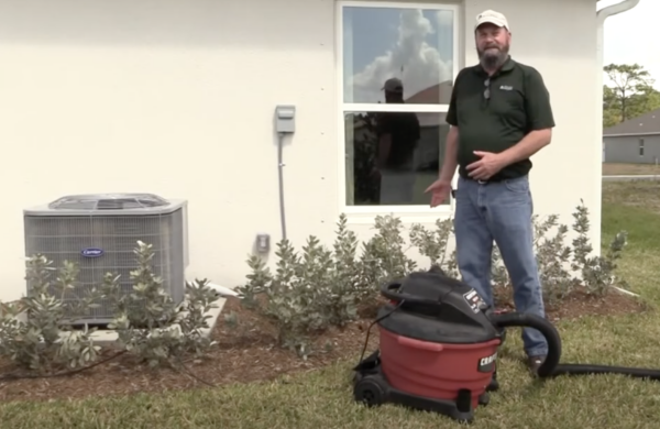 Man standing next to outdoor air conditioning unit. 